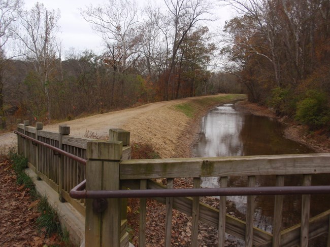 A wooden railing of a bridge over the canal in winter.