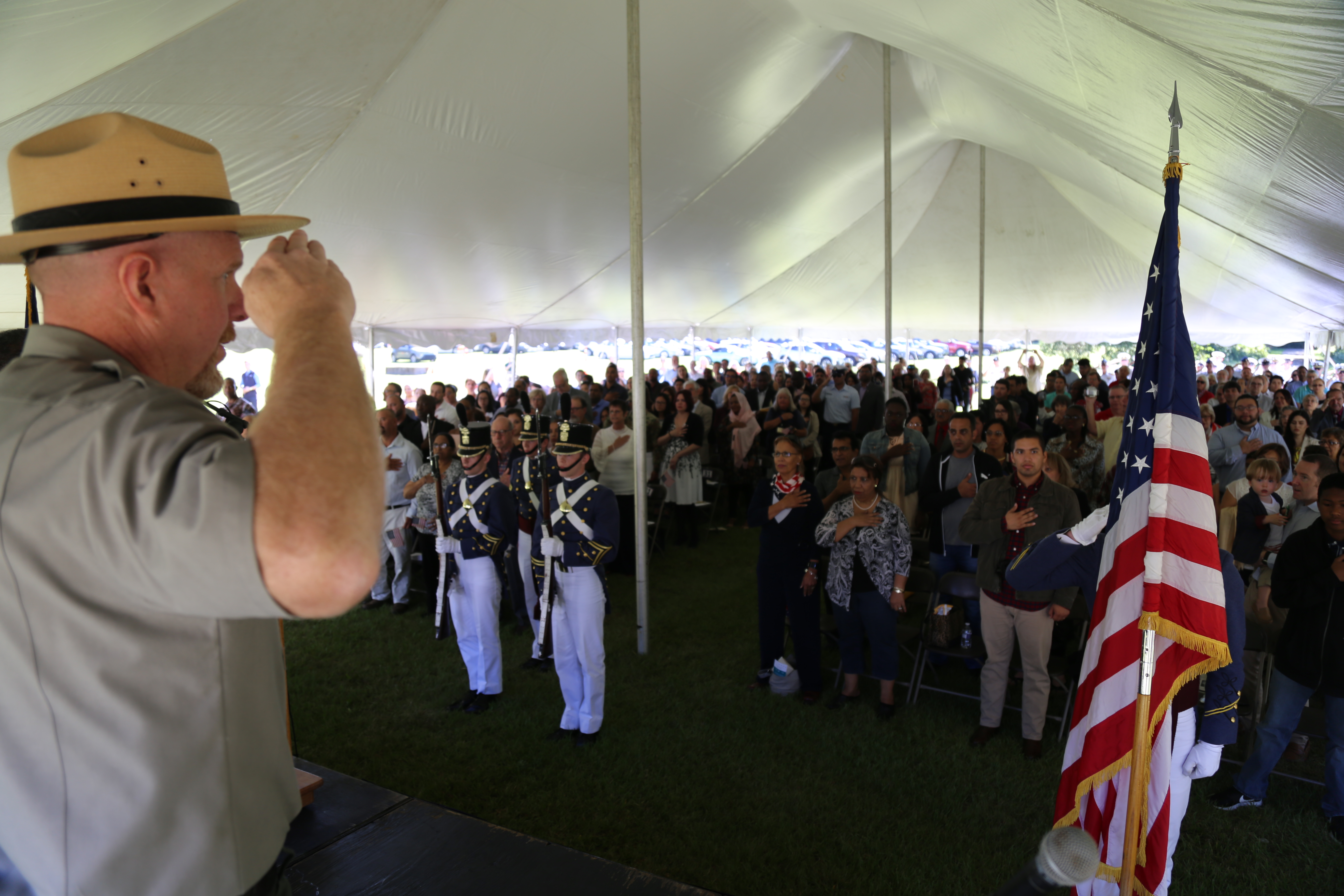 Ranger saluting the US Flag with new US citizens in background standing