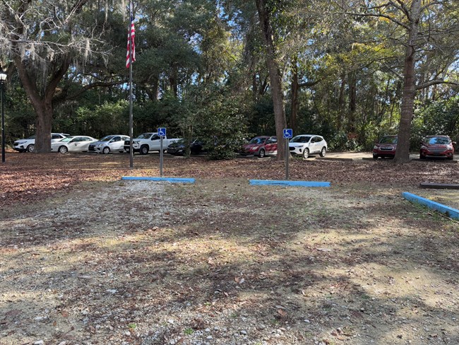 A small gravel parking lot with two spaces marked as accessible.