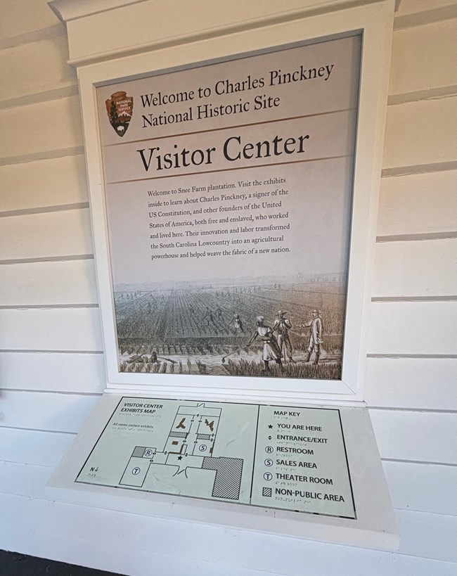 A tactile map on a porch. There is a large upright sign behind the cantilevered tactile map with information about the site.