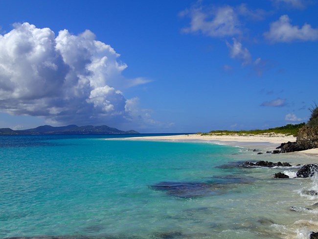 photo of the beach at Buck Island with rain in the background