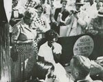 Elizabeth Eckford waits on a bus bench as segregationist protestors surround her, September 4, 1957.