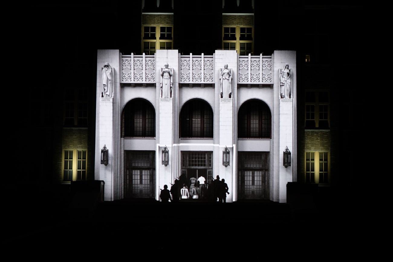 The entrance of Central High School during a September 2017 performance of Imagine if Buildings Could Talk, a 3D mapping video program. This segment features animated images of the Little Rock Nine entering Central High under military escort.