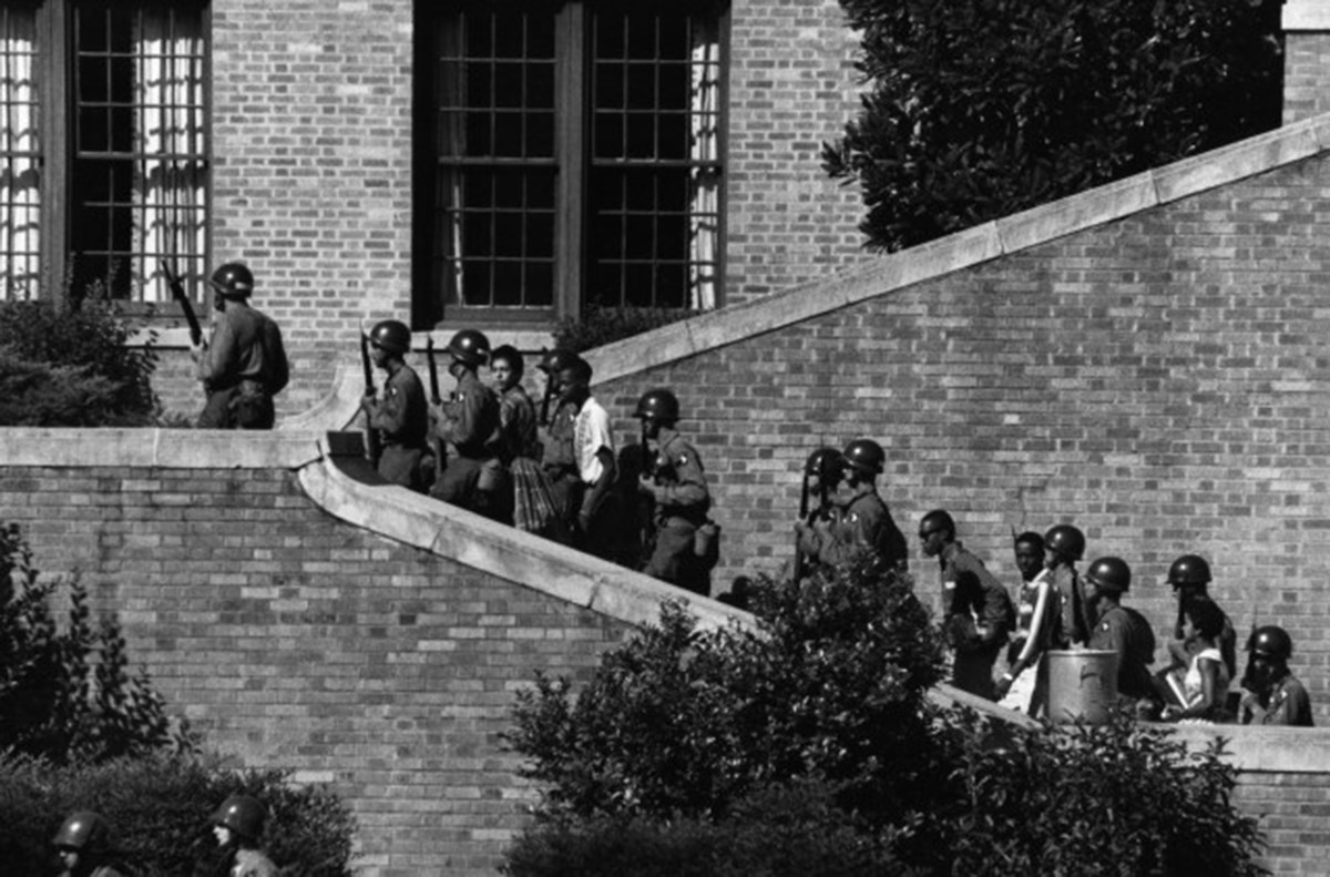 The Little Rock Nine are escorted up the stairs leading into Central High School under the protection of the 101st Airborne.