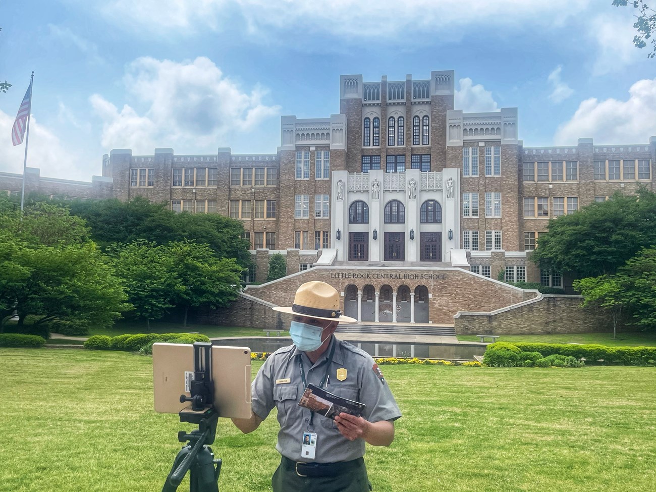 A park ranger uses an iPad & tripod to present a virtual program in front of Central Hiigh School.