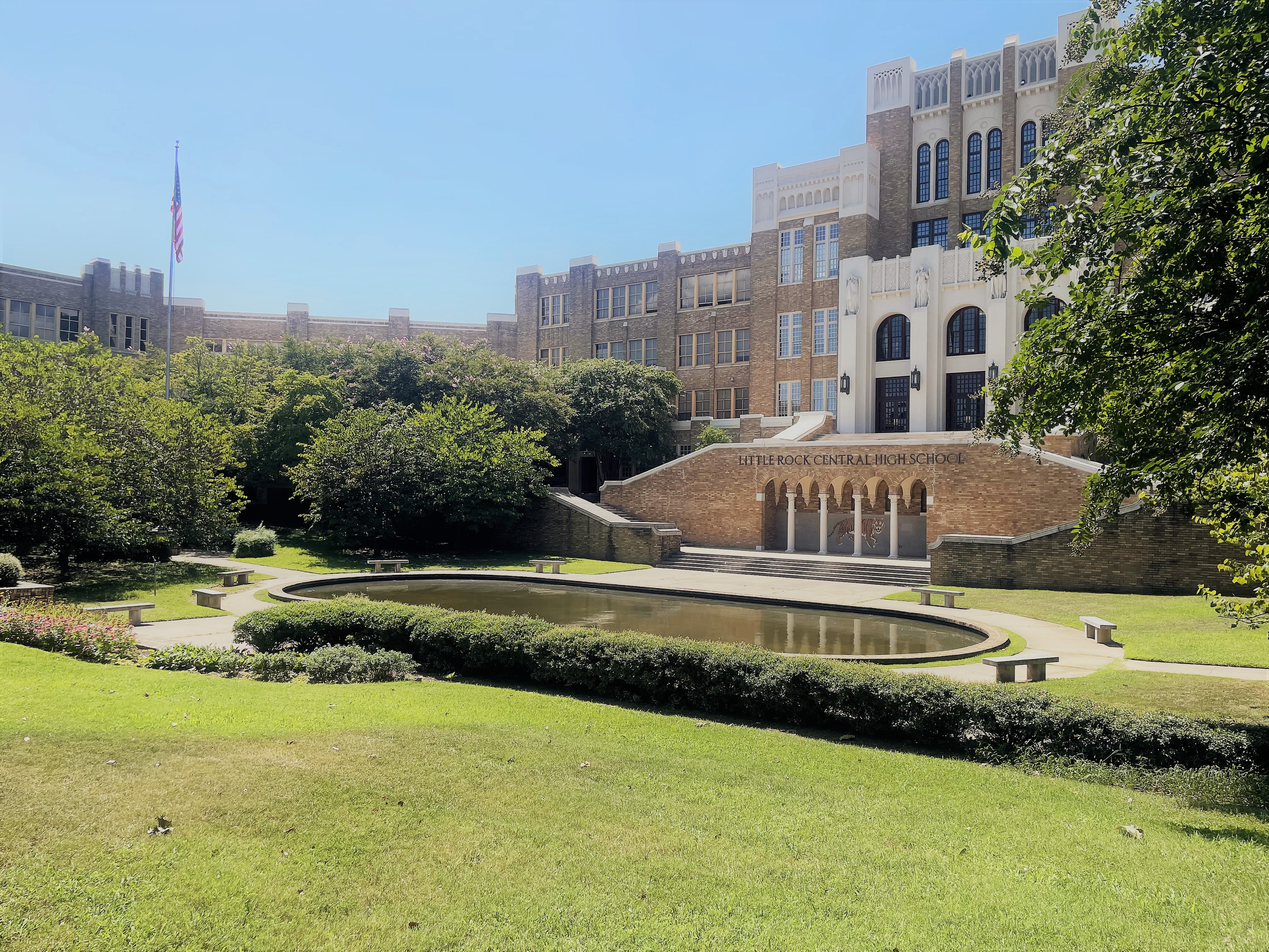 The main landing of the school on the second story is flanked above by curved arched windows, dark steel lantern light fixtures, and four statues that rise above the main entrance's three sets of wooden double doors.
