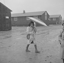 Photo courtesy of the National Archives A young resident of the Jerome Relocation Center dressed in rubber boots and carrying a parasol walks in the Arkansas rain.