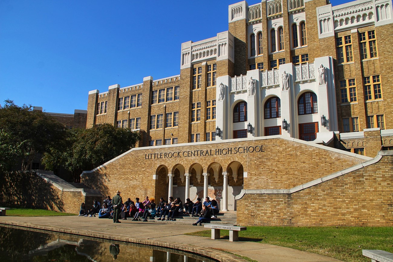 A group sits outside Little Rock Central High School as a park ranger narrates the story of desegregation and the bravery of the Little Rock Nine.