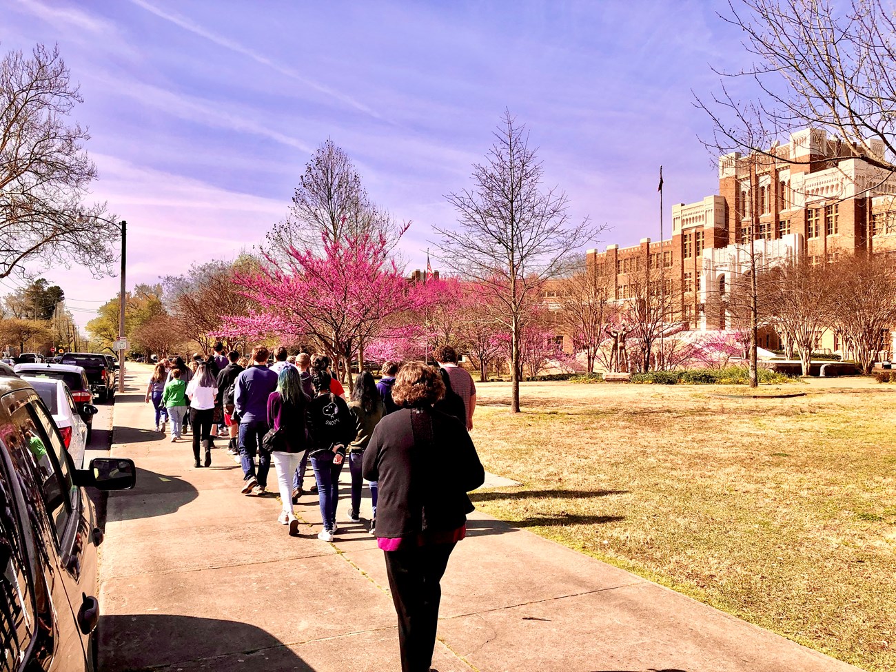 Visitors on a ranger-led streetscape tour walk by Little Rock Central High School.