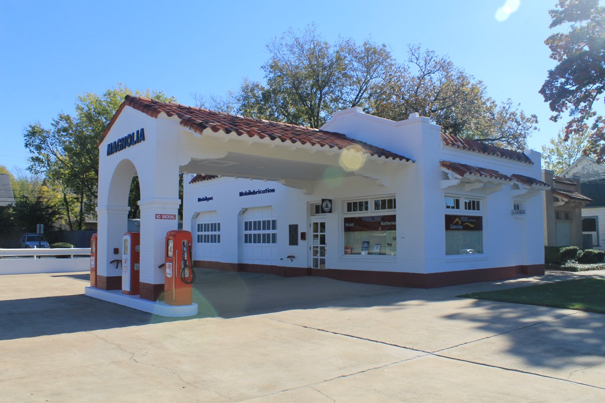 Exterior view of Magnolia Mobil Gas Station, a white stucco 1920s building with a terracotta roof.