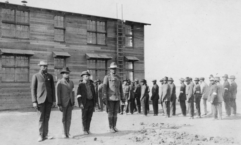 A group of men standing at attention in front of a large building