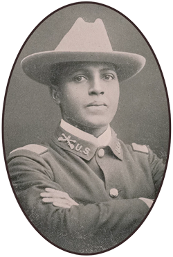 Young-TheColoredAmerican-1901-350 An African American soldier wearing a flat brim, light-colored hat with dark-colored blouse and his arms crossed at his chest