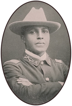 Young-TheColoredAmerican-1901-350 An African American soldier wearing a flat brim, light-colored hat with dark-colored blouse and his arms crossed at his chest