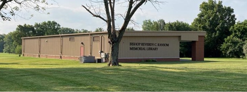 A tan and brown, one-story building with text on front that reads BISHOP REVERDY C. RANSON MEMORIAL LIBRARY