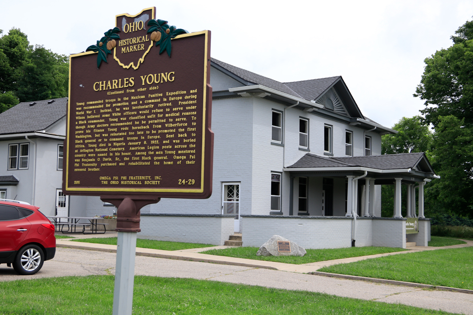 Youngsholm SW View A large bronze plaque about Charles Young sits in the foreground while a large gray house is in the background