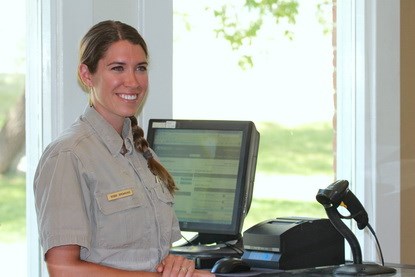 Employee Robbi Browning stands behind information desk, ready to assist visitors