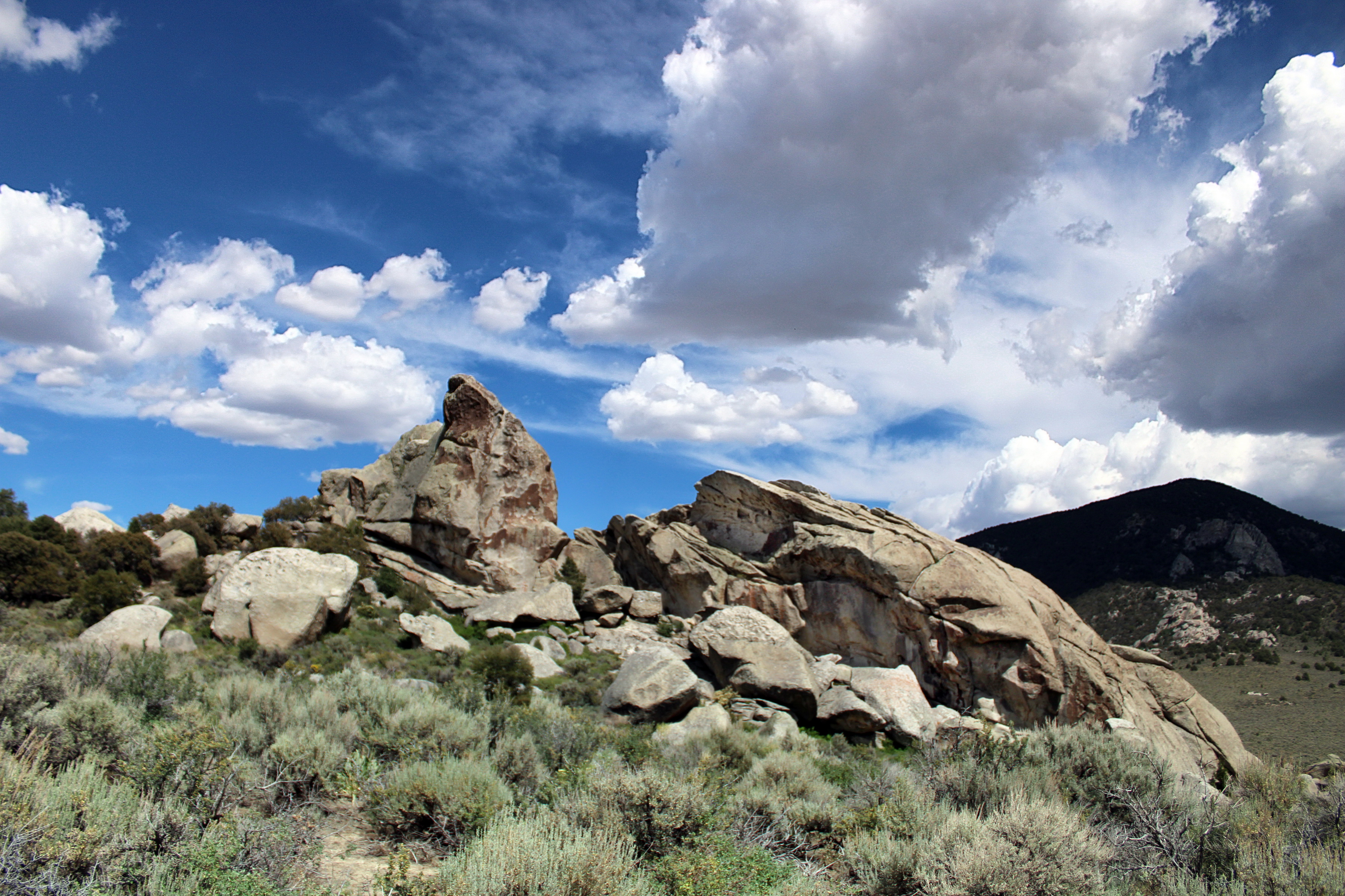 Granite rock formations under a blue sky with fluffy clouds.