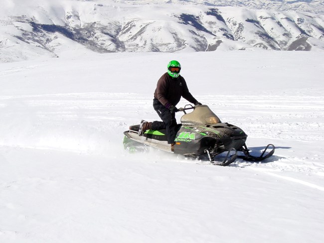 A person is riding a snowmobile through a snowy landscape