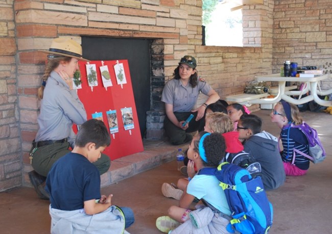 Two rangers talking with seated children near fireplace. Two rangers talking with seated children near fireplace.