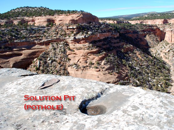 Photo of a circular water filled pothole, hollowed out in sandstone.