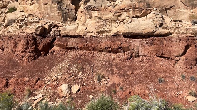 brick red rocks below steep cliffs