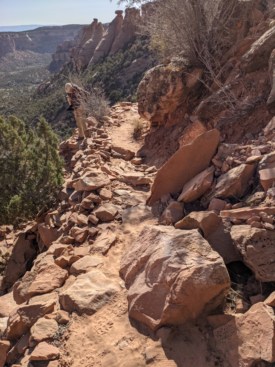 Narrow trail on steep slope with boulders sliding onto trail.