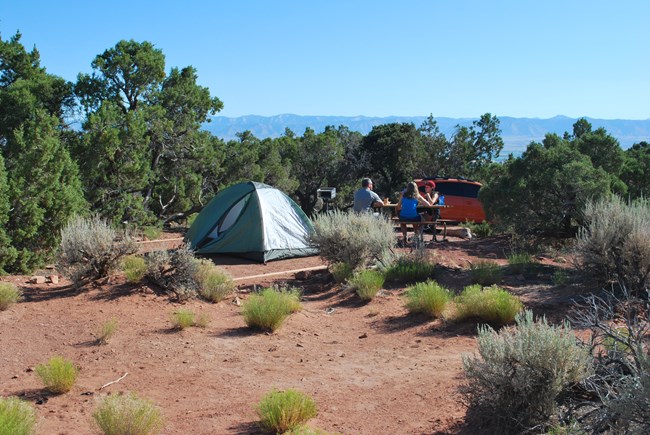 Campers sitting at a table next to their tent