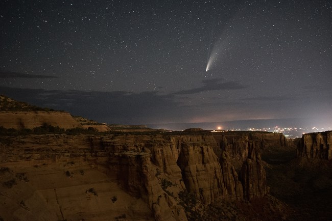 night sky with comet above dark canyon cliffs
