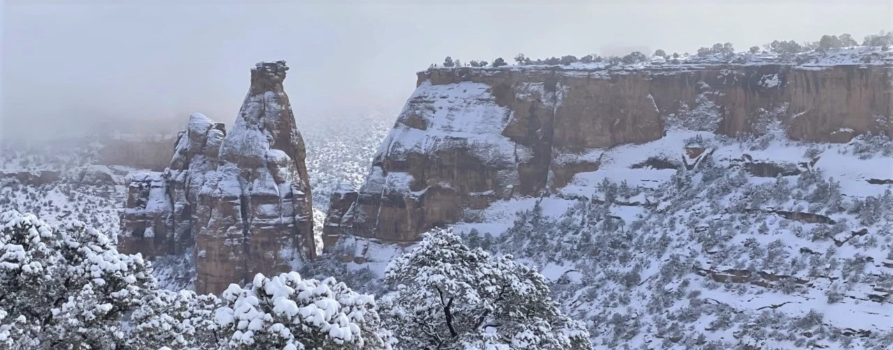 Winter in Wedding Canyon Snow-covered red-rock spires and cliffs stand among white mist and snow-laden trees.