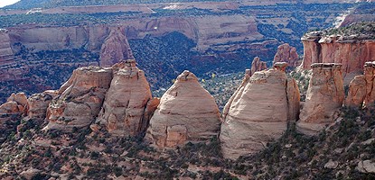 Three beehive-shaped rock formations stand in a line with other shapes, all made out of smoothed yellow-khaki sandstone. The shape is similar to old coke ovens that burned coal for the coke byproduct.