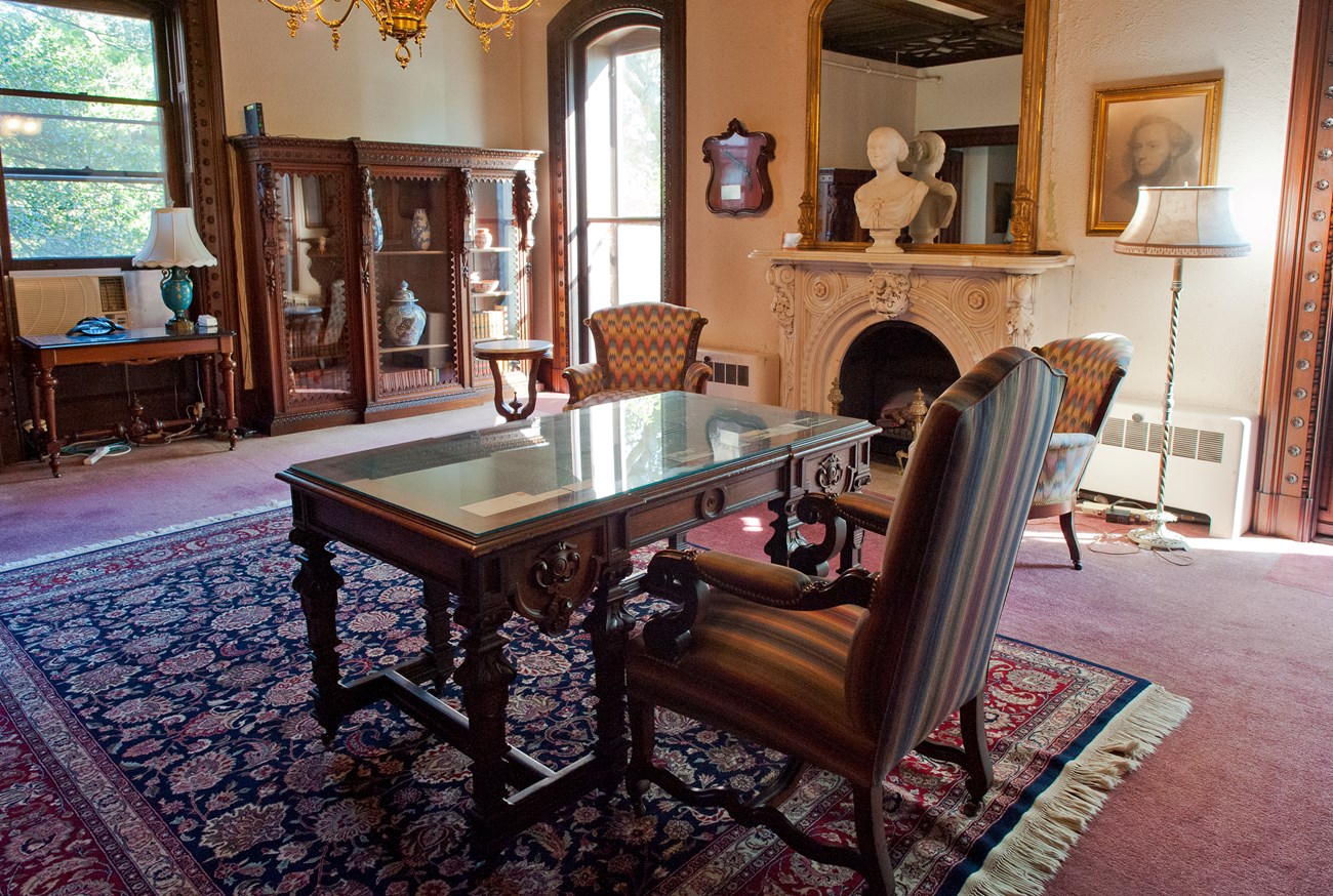 A room with multiple chairs, a table, a bookcase and a fireplace.