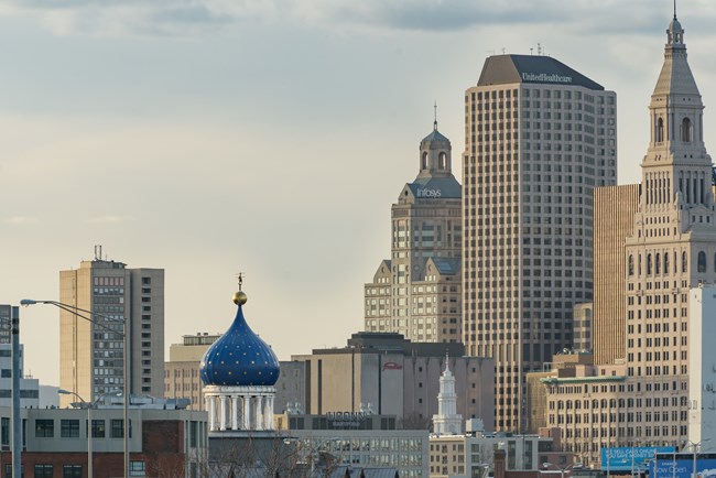 A blue onion dome, with rampant colt stands out amongst a city skyline.