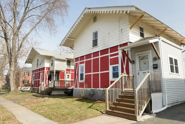A two story house with red brick exterior brick bottom and white second level.