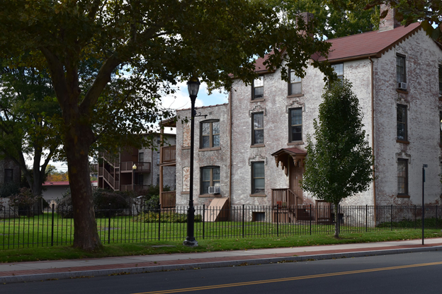 A multistory red brick building, painted white with multiple chimneys.