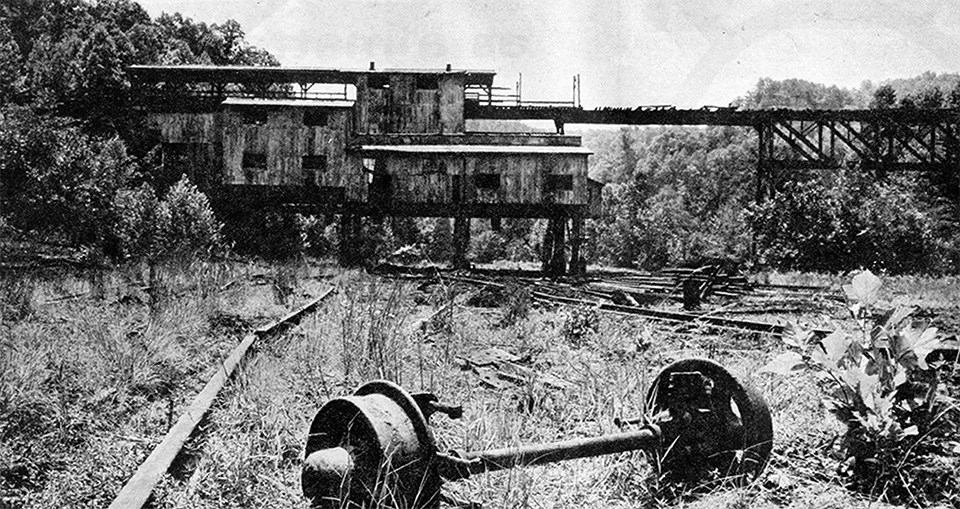 black and white photo of old tracks leading up to an old tipple bridge that once hauled coal