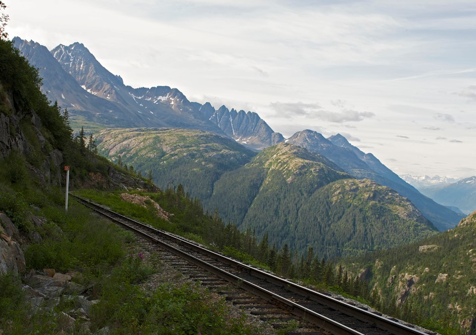 Black and white image of train tracks and mountains