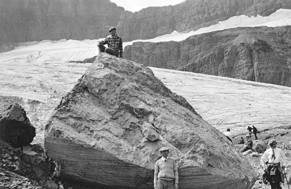 A glacier with people standing on and around it.