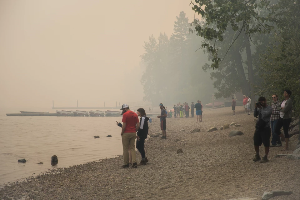 People stand on a beach in sunny weather.