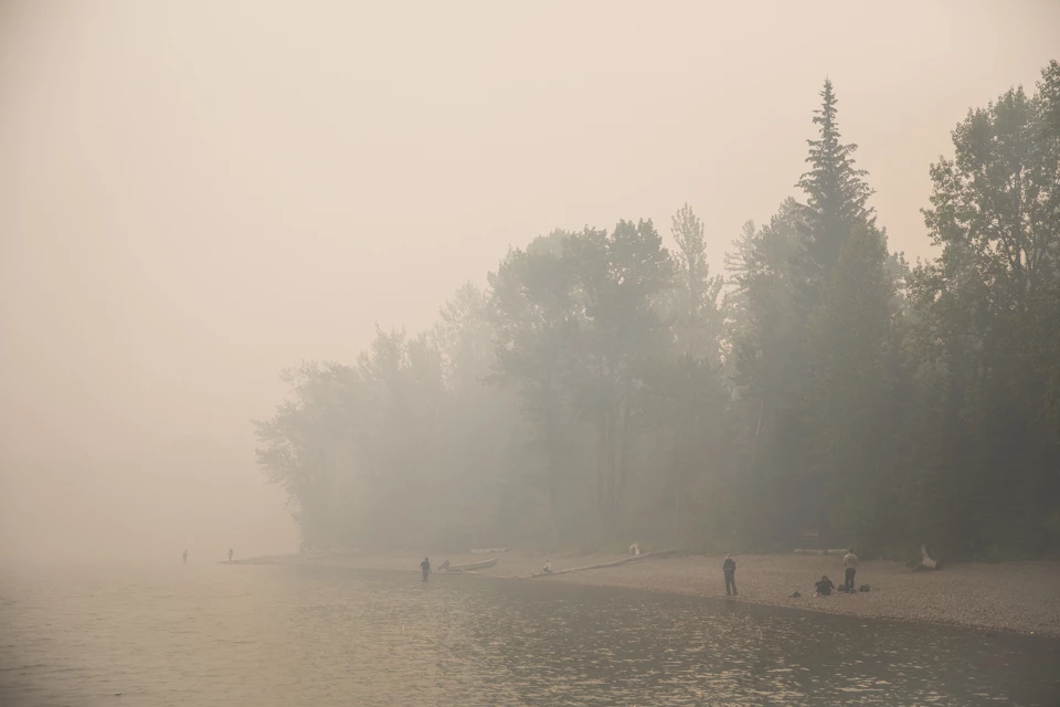 People stand on a beach in sunny weather.