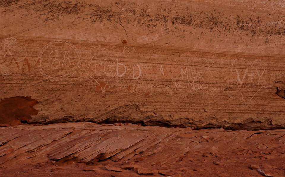 Sandstone wall covered with scratched on graffiti
