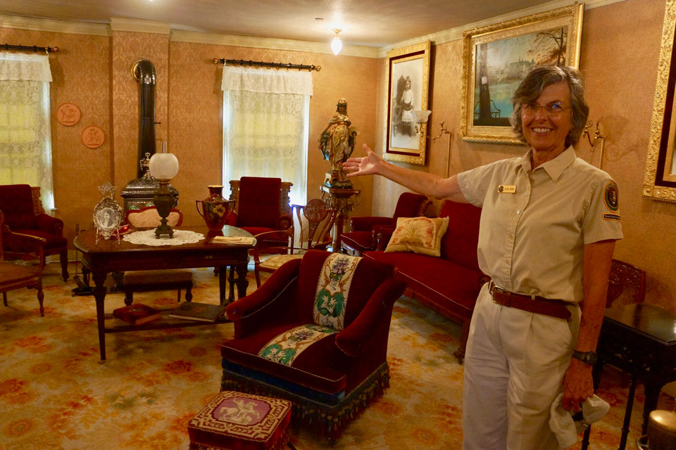 Exterior of ranch house, two story, white clapboard siding, green shutters, looking at the southeast corner.