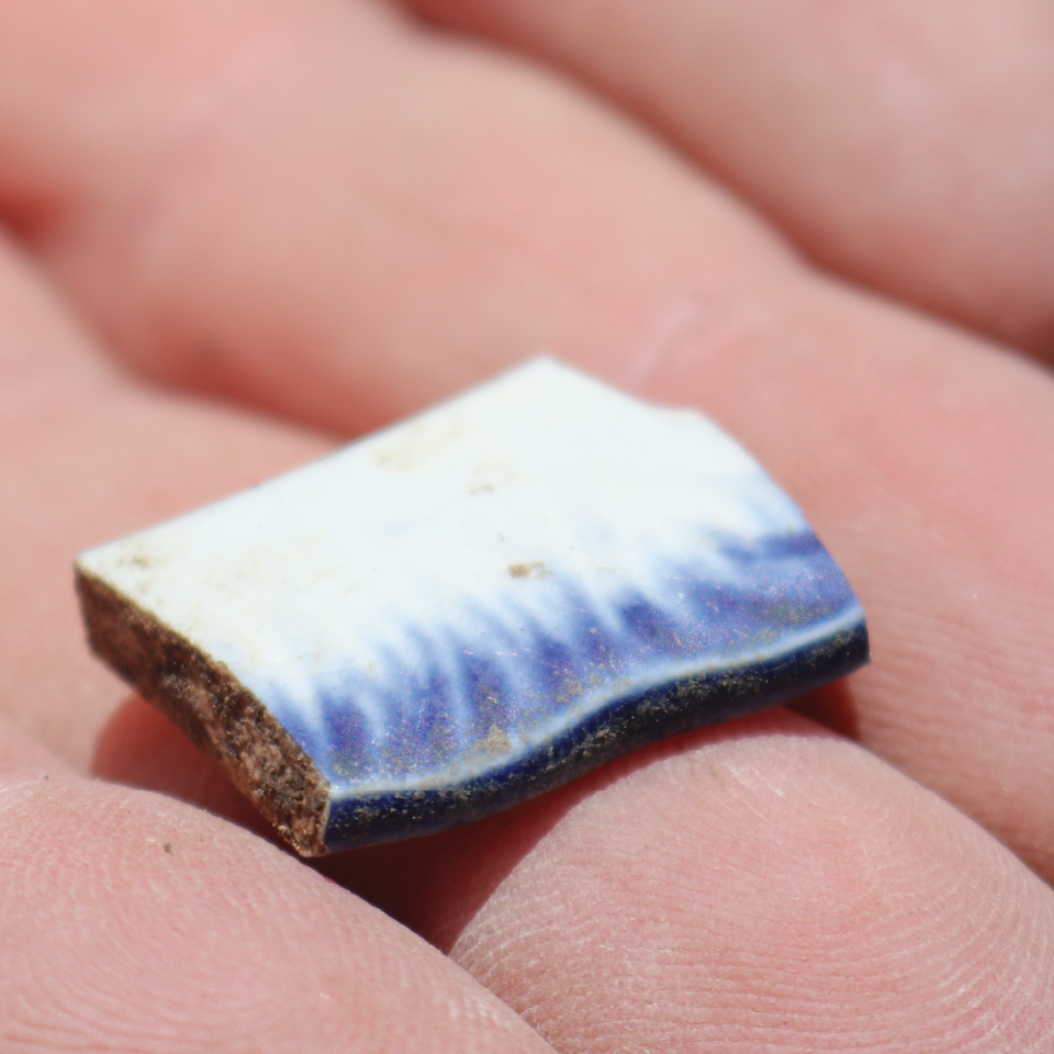 2 inch piece of brown bone-tempered pottery sherd sitting in the palm of a hand.