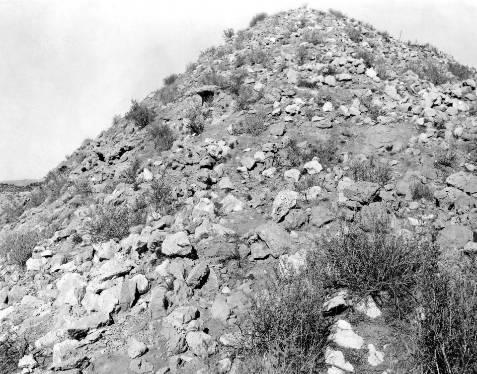 A steep hillside covered in large rocks from collapsed pueblo walls