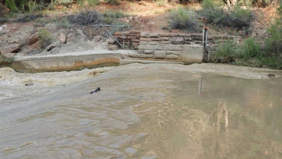 Black and white photo of six men stacking rocks near a river bank.