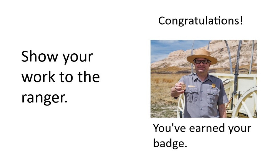 A ranger holds a Junior Ranger badge.