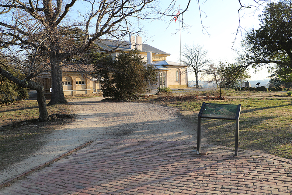 A gravel entrance to a site with run down signage.