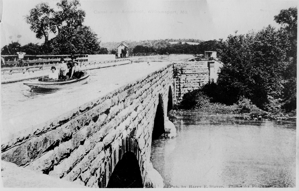 A family in a canoe boat riding along the canal over the original Conococheague Aqueduct.