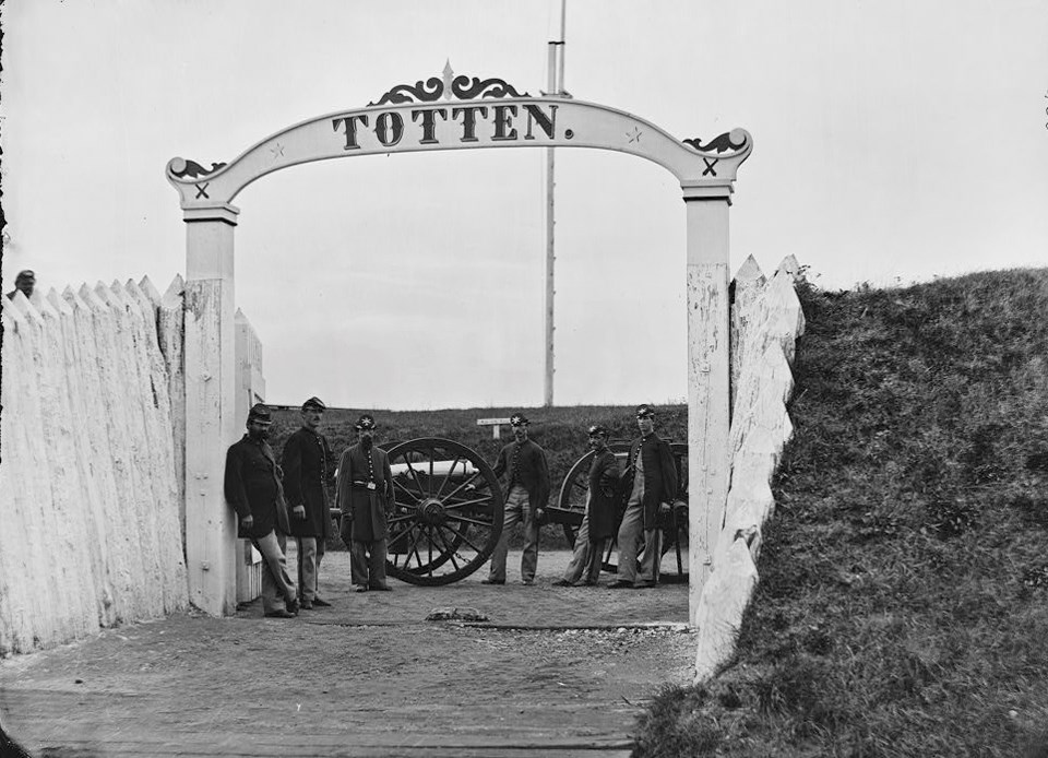 Union soldiers lean on cannons under an archway that reads "TOTTEN"