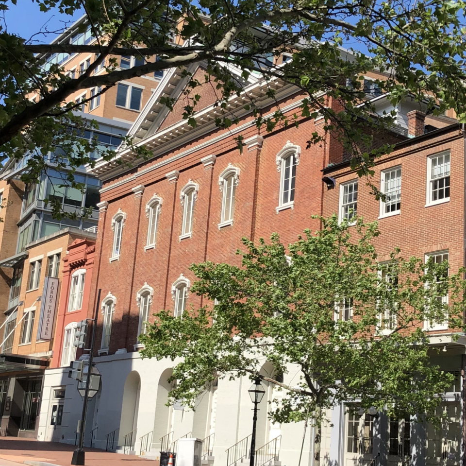 1865 Photo of Ford's Theatre with small groups of people gathered outside the front doors.