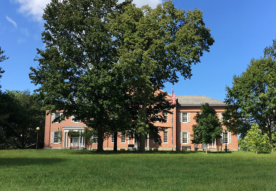 Engraving of large brick building, the sky, and trees to the side and front of the building